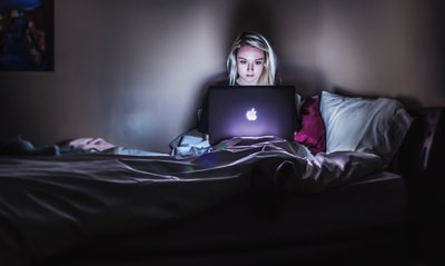 坐在床上膝上放着MacBook的女人